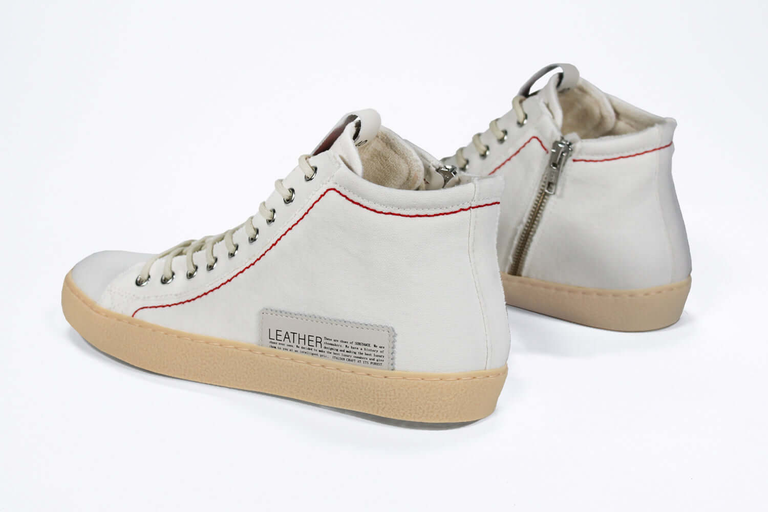 Back view of high top canvas sneaker. Canvas white upper with signature red stitching and a pale natural rubber sole.