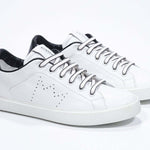 Three quarter view of low top white sneaker with black detailing and perforated crown logo on upper. Full leather upper and white rubber sole.