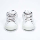 Front view of low top white sneaker with black detailing and perforated crown logo on upper. Full leather upper and white rubber sole.