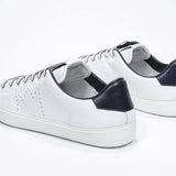 Three quarter back view of low top white sneaker with navy detailing and perforated crown logo on upper. Full leather upper and white rubber sole.