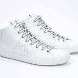 Three quarter view of mid top white sneaker with full leather upper with perforated crown logo and white sole.