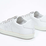 Three quarter back view of low top white sneaker with perforated crown logo on upper. Full leather upper and white rubber sole.