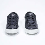 Front view of low top black sneaker with perforated crown logo on upper. Full leather upper and white rubber sole.