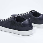 Three quarter back view of low top navy sneaker with perforated crown logo on upper. Full suede upper and white rubber sole.