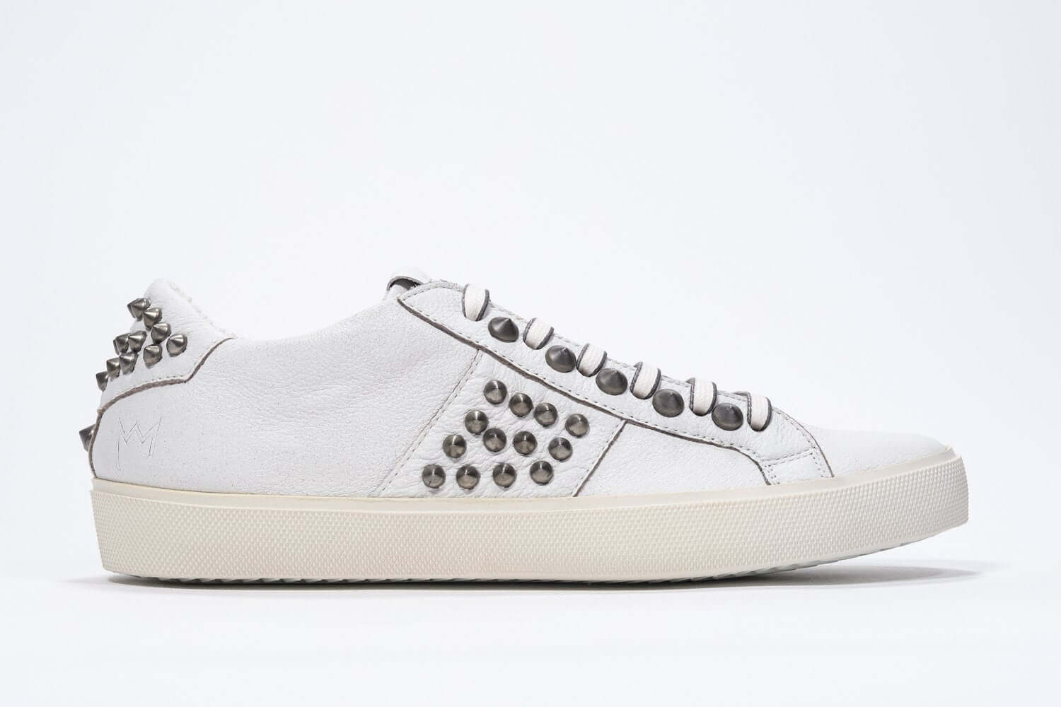 Side profile of low top white sneaker. Full leather upper with studs and vintage rubber sole.
