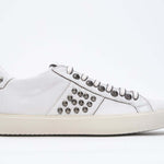 Side profile of low top white sneaker. Full leather upper with studs and vintage rubber sole.