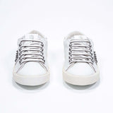 Front view of low top white sneaker. Full leather upper with studs and vintage rubber sole.