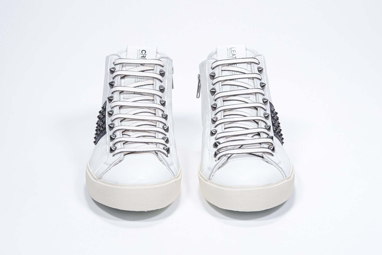 Front view of mid top white and navy sneaker. Full leather upper with studs, an internal zip and vintage rubber sole.
