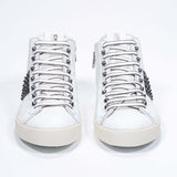 Front view of mid top white and navy sneaker. Full leather upper with studs, an internal zip and vintage rubber sole.
