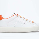 Side profile of low top white sneaker with orange detailing and perforated crown logo on upper. Full leather upper and white rubber sole.