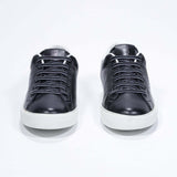 Front view of low top black sneaker with white detailing and perforated crown logo on upper. Full leather upper and white rubber sole.