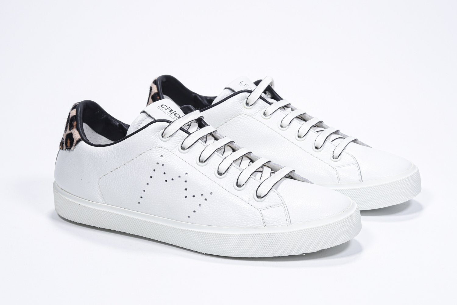 Three quarter front view of low top white sneaker with leopard print detailing and perforated crown logo on upper. Full leather upper and white rubber sole.