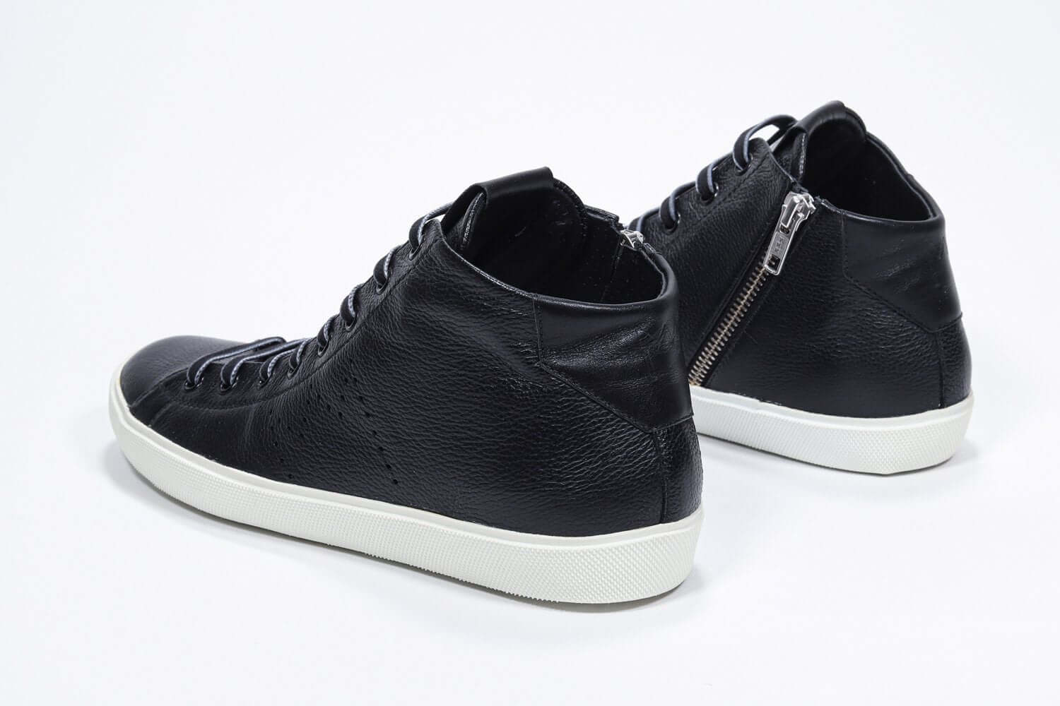 Three quarter back view of mid top black sneaker with full leather upper with perforated crown logo, internal zip and white sole.
