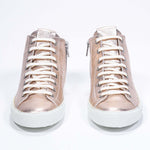 Front view of mid top rose-gold sneaker with full leather upper with perforated crown logo, internal zip and white sole.