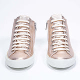 Front view of mid top rose-gold sneaker with full leather upper with perforated crown logo, internal zip and white sole.