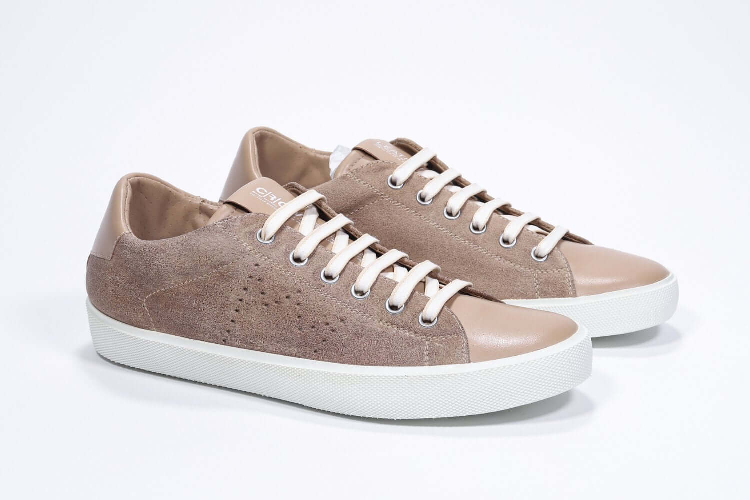 Three quarter front view of low top cuoio sneaker with perforated crown logo on upper. Full suede upper and white rubber sole.