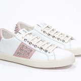 Three quarter front view of low top white and pale pink sneaker. Full leather upper with studs and vintage rubber sole.