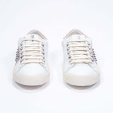 Front view of low top white and pale pink sneaker. Full leather upper with studs and vintage rubber sole.