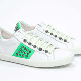 Three quarter front view of low top white and neon green sneaker. Full leather upper with studs and white rubber sole.