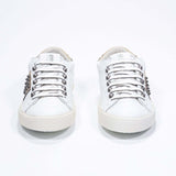 Front view of low top white and metallic gold sneaker. Full leather upper with studs and vintage rubber sole.