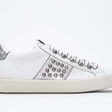 Side profile of low top white and metallic silver sneaker. Full leather upper with studs and vintage rubber sole.