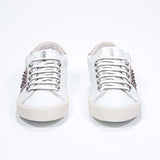 Front view of low top white and metallic rose sneaker. Full leather upper with studs and vintage rubber sole.