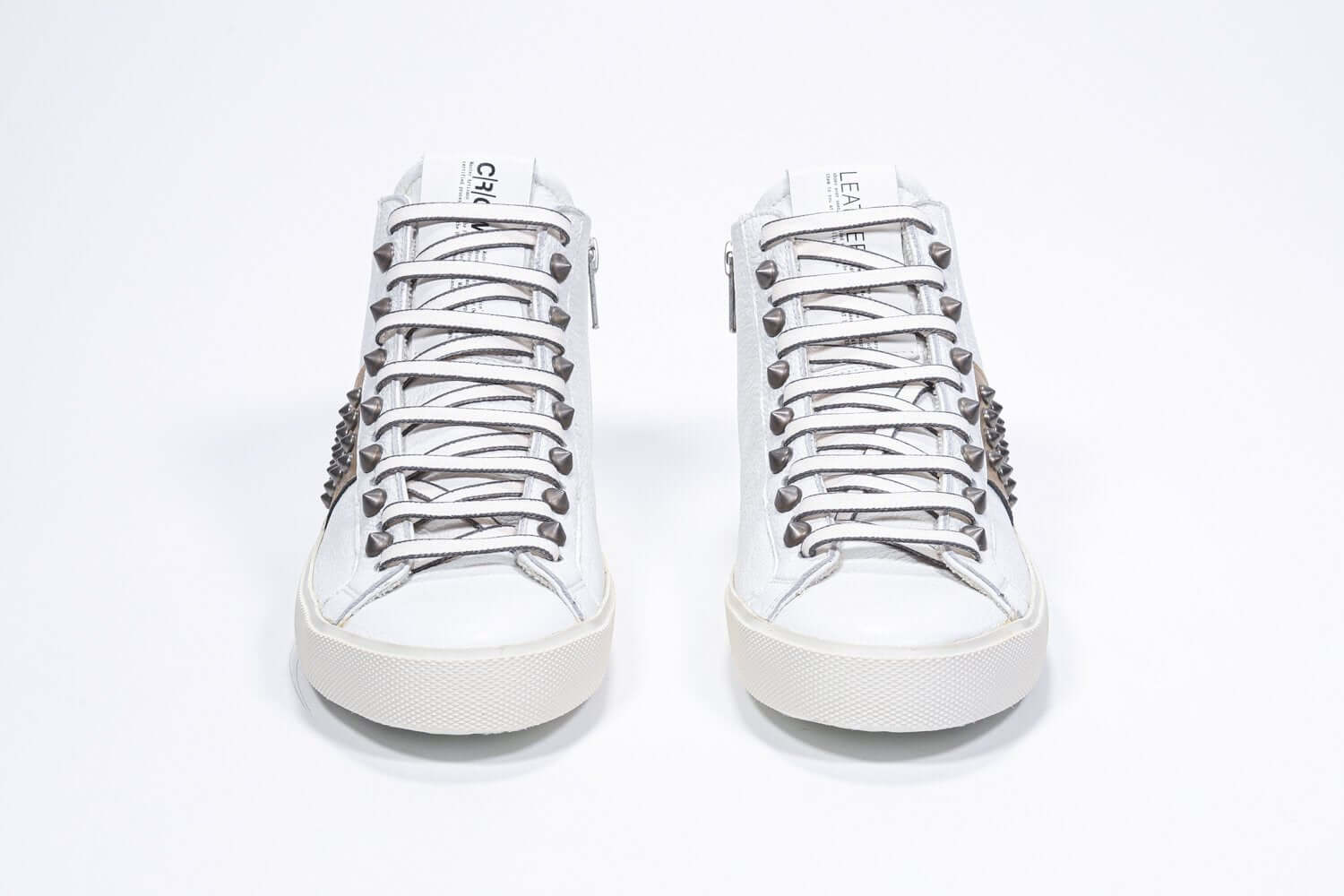 Front view of mid top white and metallic gold sneaker. Full leather upper with studs, an internal zip and vintage rubber sole.